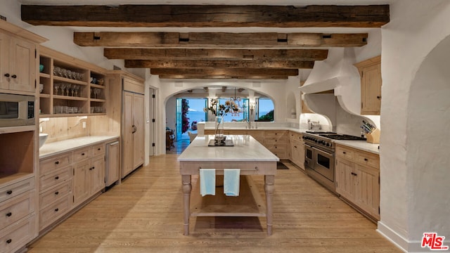 kitchen featuring light brown cabinetry, stainless steel appliances, a notable chandelier, a kitchen island, and light hardwood / wood-style floors