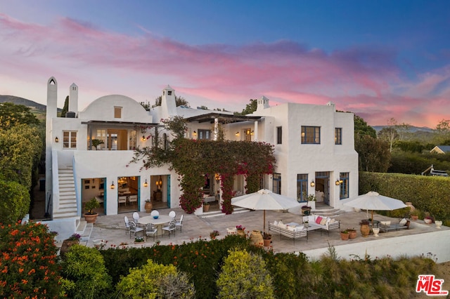 back house at dusk featuring an outdoor living space and a patio