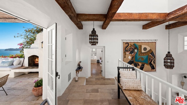 hallway with coffered ceiling, beam ceiling, tile floors, and a water view