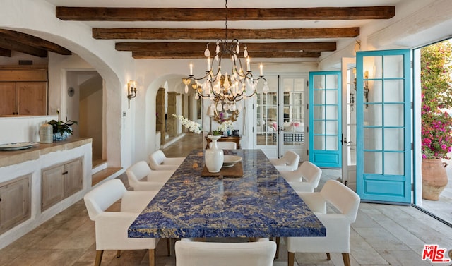 dining space featuring a notable chandelier, beam ceiling, and french doors