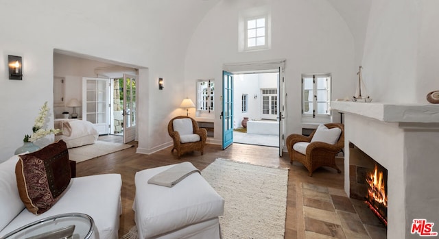 living area featuring french doors, plenty of natural light, and high vaulted ceiling