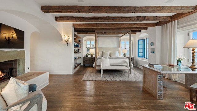 bedroom with beamed ceiling, a fireplace, and dark wood-type flooring