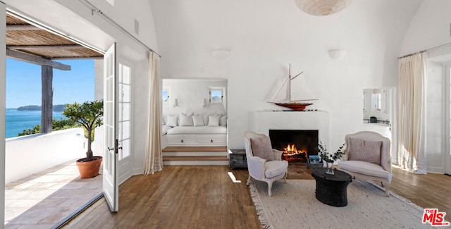 living area with wood-type flooring, a high ceiling, and a water view