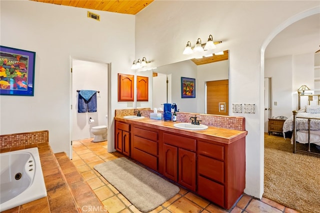 bathroom featuring tile flooring, wood ceiling, dual bowl vanity, high vaulted ceiling, and toilet