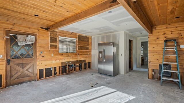 unfurnished living room with wood ceiling, beam ceiling, and wood walls