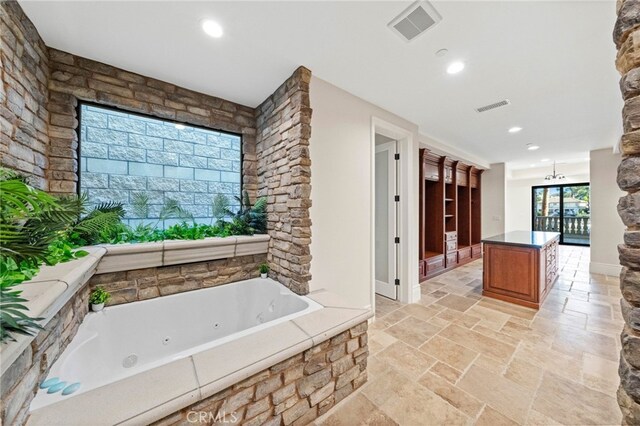 bathroom with a relaxing tiled bath, vanity, and tile floors