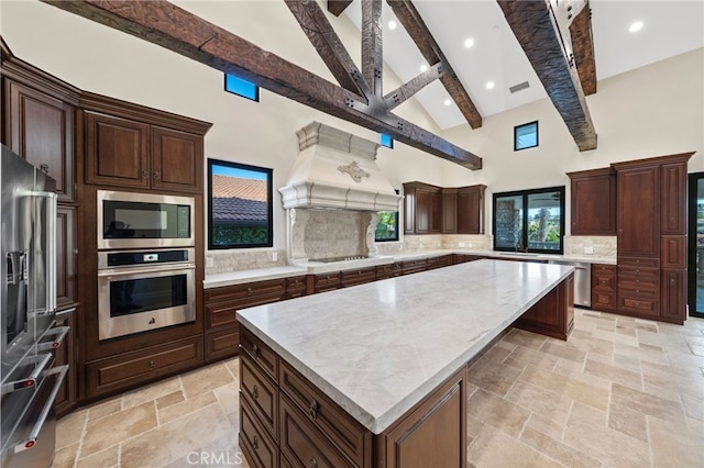 kitchen featuring premium range hood, appliances with stainless steel finishes, beam ceiling, a kitchen island, and tasteful backsplash