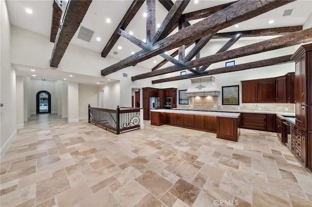 kitchen featuring backsplash, premium range hood, high vaulted ceiling, and light tile floors