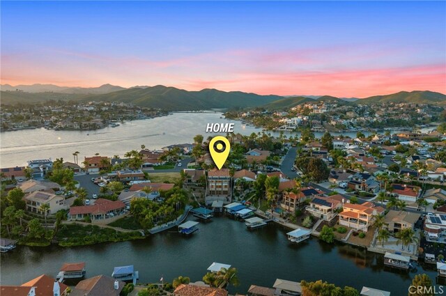 aerial view at dusk featuring a water and mountain view