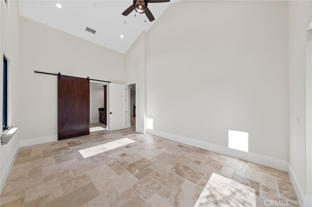 unfurnished bedroom featuring a barn door, ceiling fan, high vaulted ceiling, and light tile floors