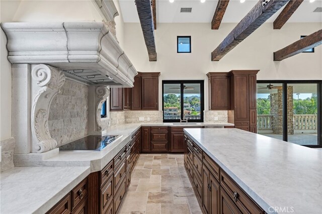 kitchen featuring ceiling fan, tasteful backsplash, beamed ceiling, light tile floors, and black electric stovetop