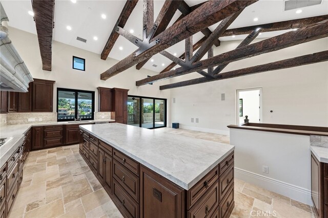 kitchen with high vaulted ceiling, tasteful backsplash, beam ceiling, a center island, and light tile floors