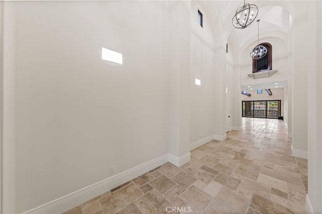 corridor featuring a notable chandelier, a high ceiling, and light tile floors