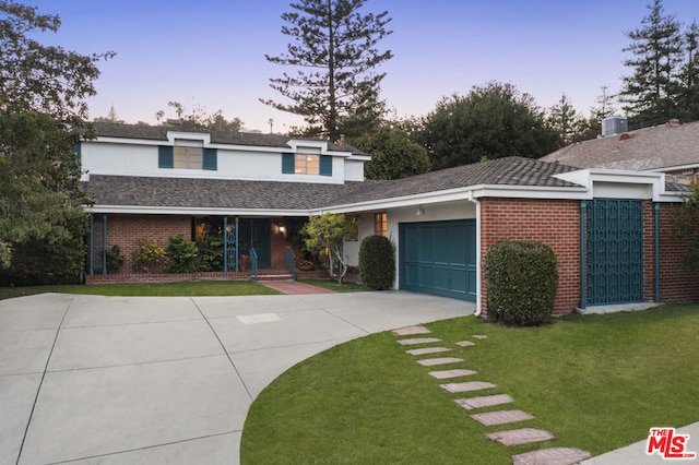 view of property featuring a lawn, central air condition unit, and a garage