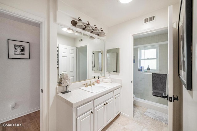 bathroom featuring tile patterned floors, vanity, toilet, and a shower with shower door