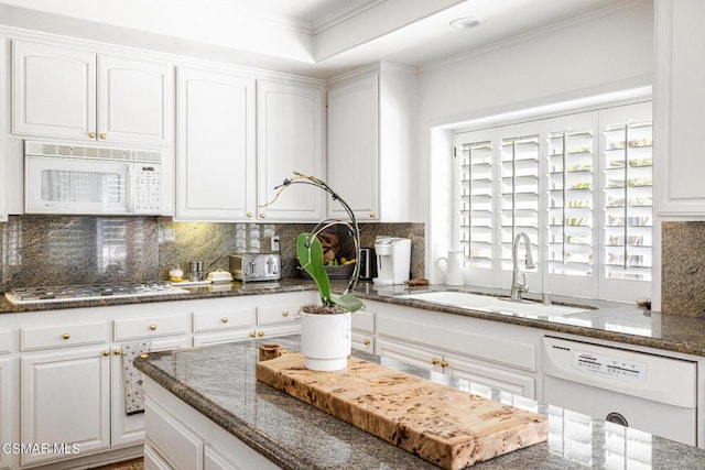 kitchen with white cabinetry, sink, dark stone counters, and white appliances