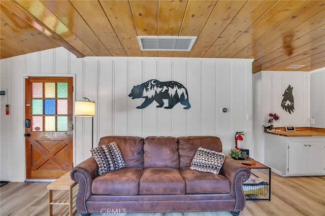 living room featuring lofted ceiling, light wood-type flooring, and wooden ceiling