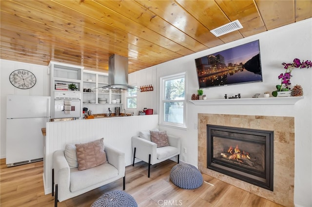 interior space with wood ceiling, wood-type flooring, and a tiled fireplace