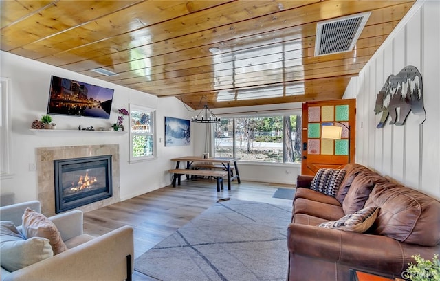 living room featuring light wood-type flooring, a fireplace, and wooden ceiling