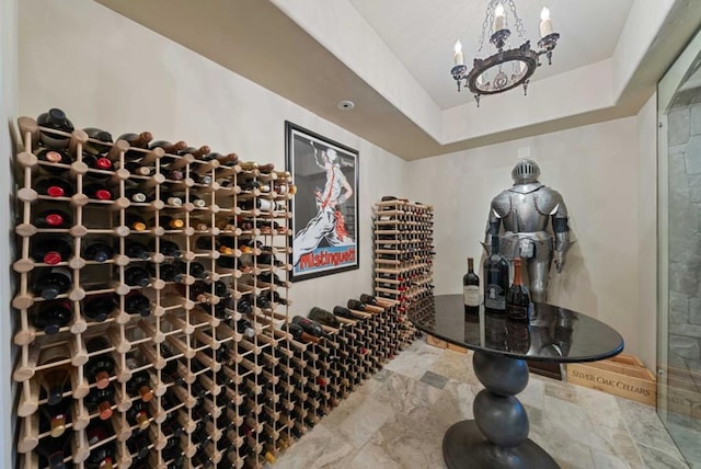 wine area featuring a tray ceiling and an inviting chandelier