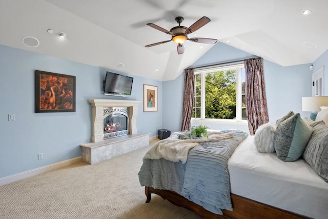 carpeted bedroom with a high end fireplace, vaulted ceiling, and ceiling fan