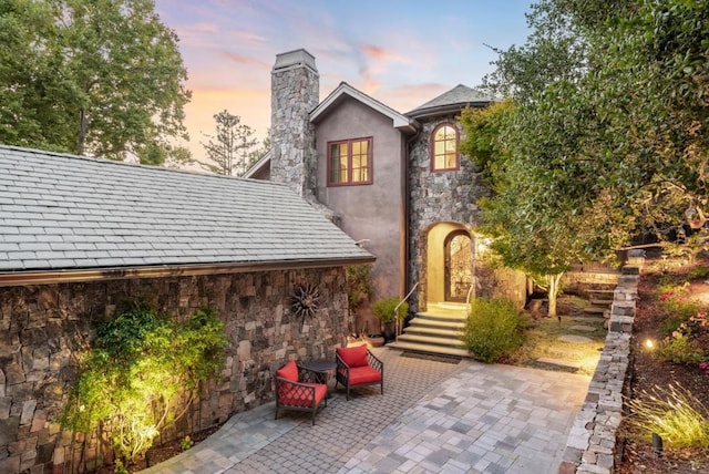 back house at dusk featuring a patio area