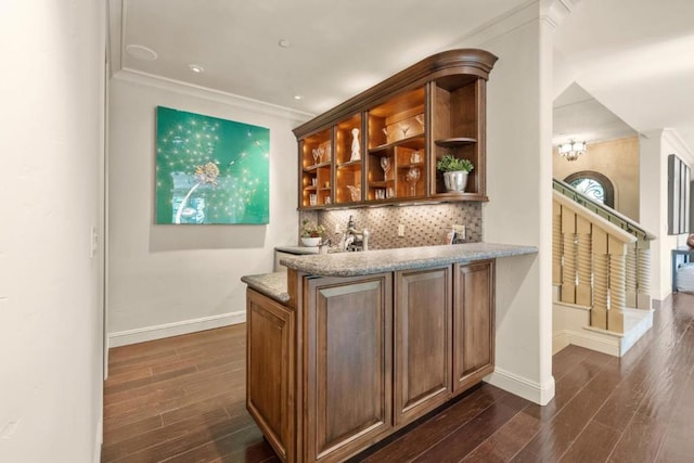 bar featuring decorative backsplash, dark hardwood / wood-style flooring, light stone counters, and crown molding