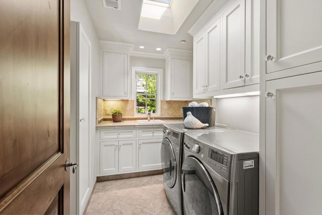 laundry room featuring a skylight, sink, cabinets, separate washer and dryer, and crown molding