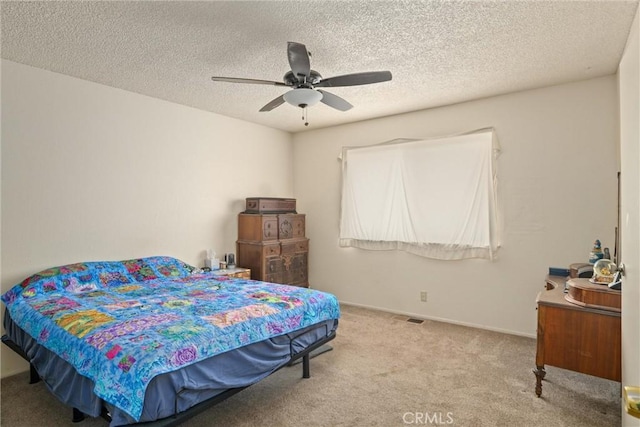 bedroom featuring a textured ceiling, light colored carpet, and ceiling fan