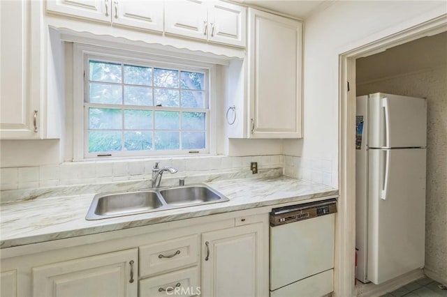 kitchen with light stone countertops, white appliances, white cabinetry, and sink