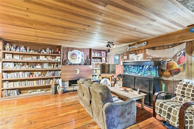 sitting room with hardwood / wood-style floors, built in features, wood ceiling, and wooden walls