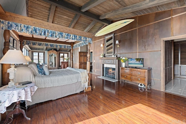 bedroom with beamed ceiling, high vaulted ceiling, a tiled fireplace, wood finished floors, and wood ceiling