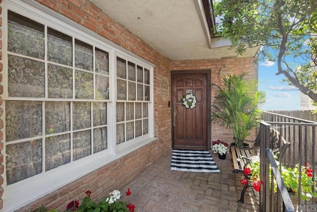 entrance to property featuring brick siding and fence