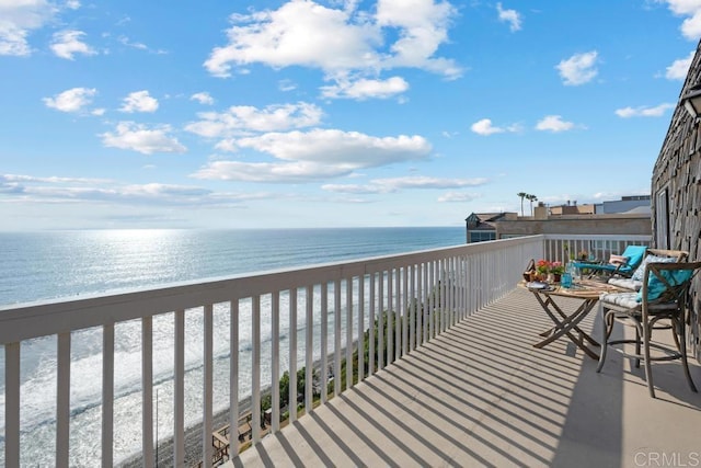 balcony featuring a view of the beach and a water view