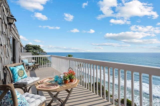 balcony with a water view and a view of the beach