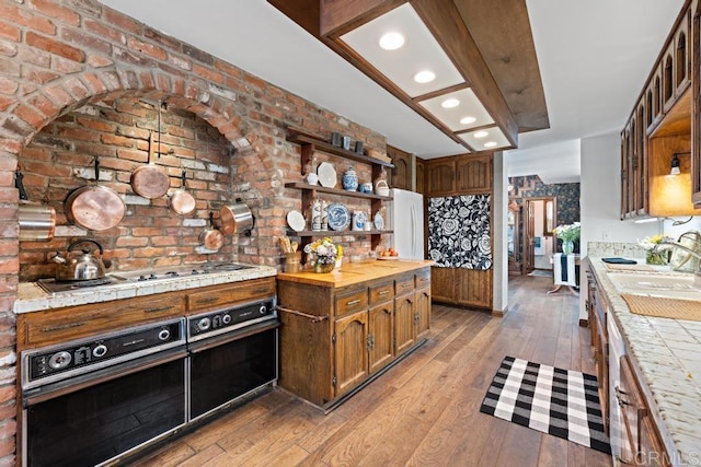 kitchen with a sink, light wood-style flooring, white appliances, and open shelves