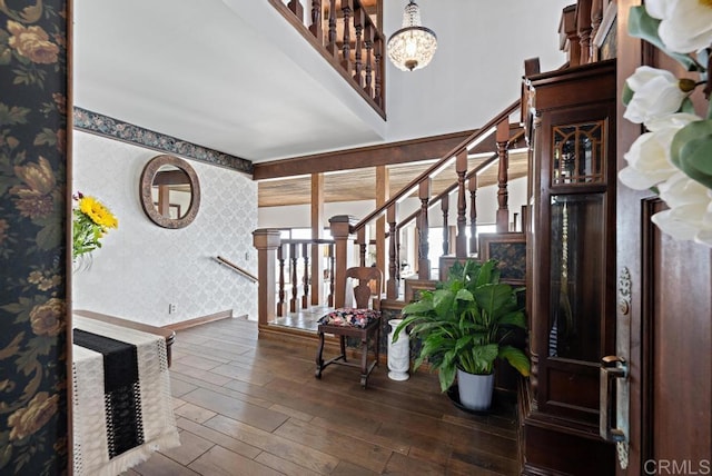 foyer featuring hardwood / wood-style flooring, wallpapered walls, baseboards, a chandelier, and stairs