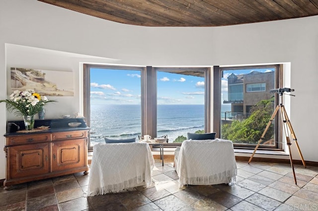 living area with wooden ceiling, baseboards, stone tile floors, and a water view