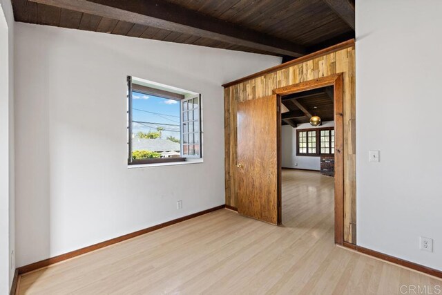 spare room with wooden ceiling, wood finished floors, and vaulted ceiling with beams