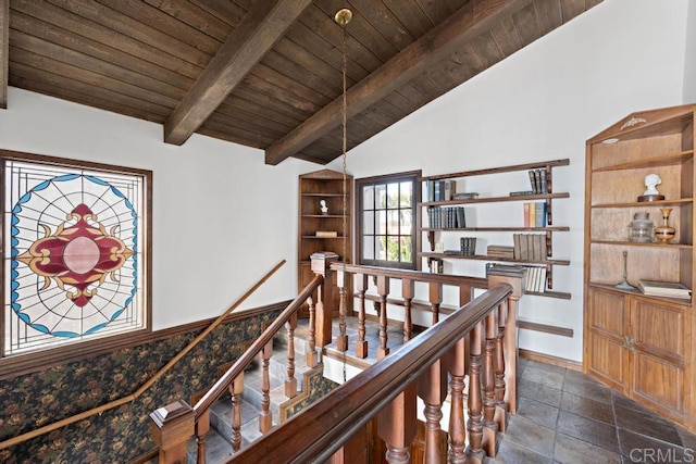 hall featuring an upstairs landing, lofted ceiling with beams, stone tile floors, wood ceiling, and baseboards
