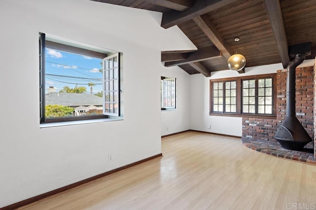 unfurnished living room featuring wood finished floors, a wood stove, vaulted ceiling with beams, baseboards, and wood ceiling