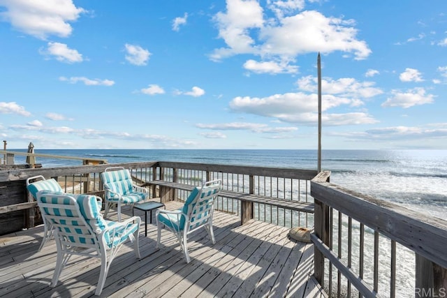 wooden deck featuring a beach view and a water view