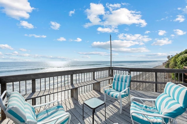 wooden terrace featuring a beach view and a water view