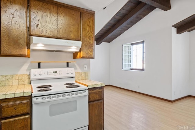 kitchen featuring tile counters, under cabinet range hood, light wood-type flooring, brown cabinetry, and electric range