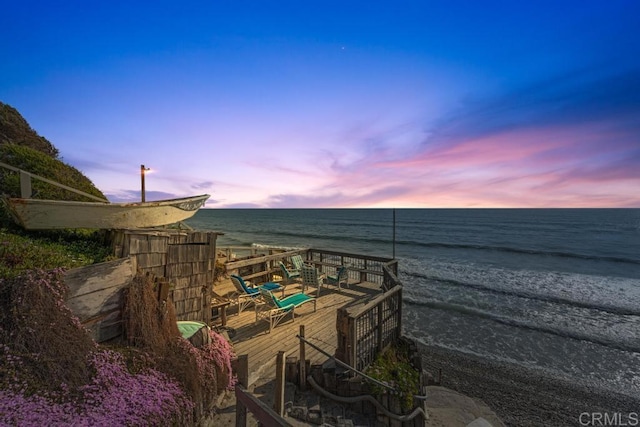 surrounding community featuring a view of the beach and a deck with water view