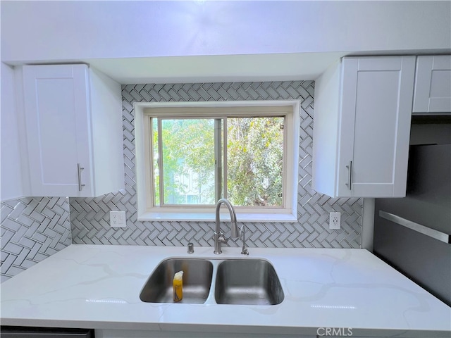 kitchen with sink, white cabinetry, and light stone countertops