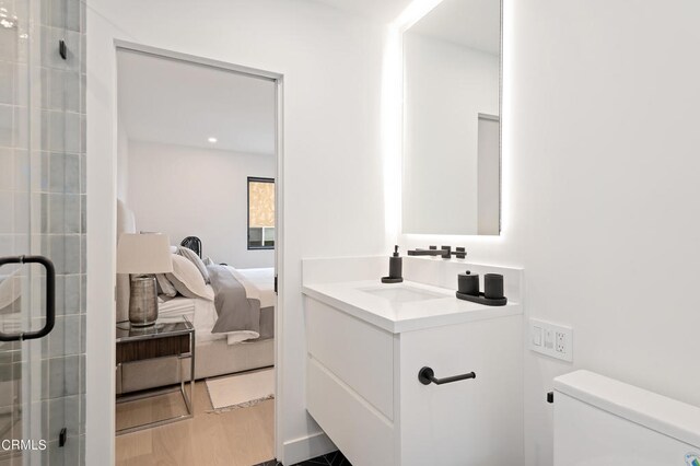 bathroom with a shower with shower door, vanity, and toilet