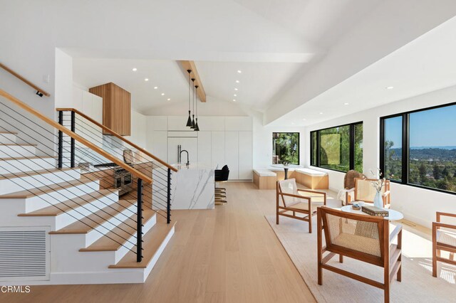 interior space featuring vaulted ceiling with beams, sink, and light hardwood / wood-style flooring