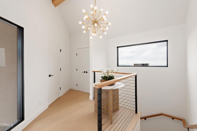 corridor with an inviting chandelier, light hardwood / wood-style flooring, and lofted ceiling with beams