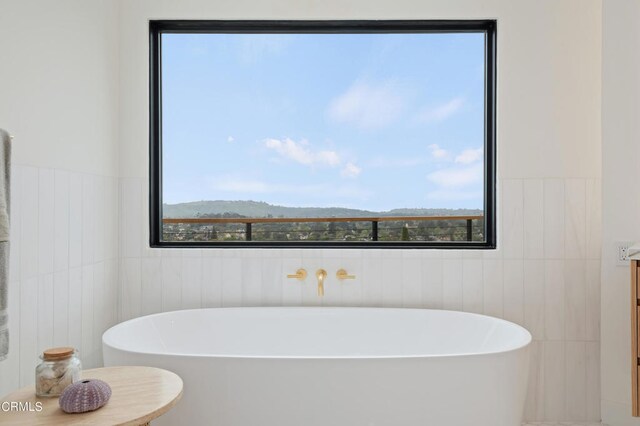 bathroom with tile walls and a bathtub